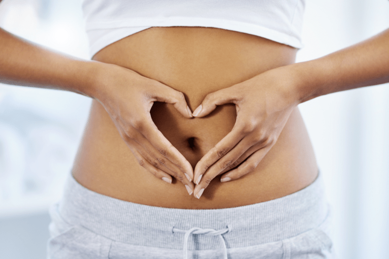 A woman expresses love for her gut health, forming a heart shape over her abdomen. Promoting wellness and self-care through a healthy relationship with her digestive system.