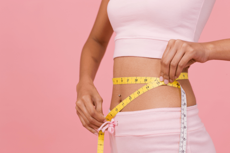 Joyful woman measuring her waist, showcasing a remarkable weight loss transformation and celebrating her achievements in a healthy lifestyle journey.