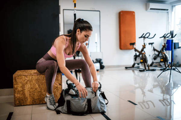 Empowered and organized: Fit woman effortlessly organizes her gym bag post-workout, embodying the essence of a successful fitness journey.